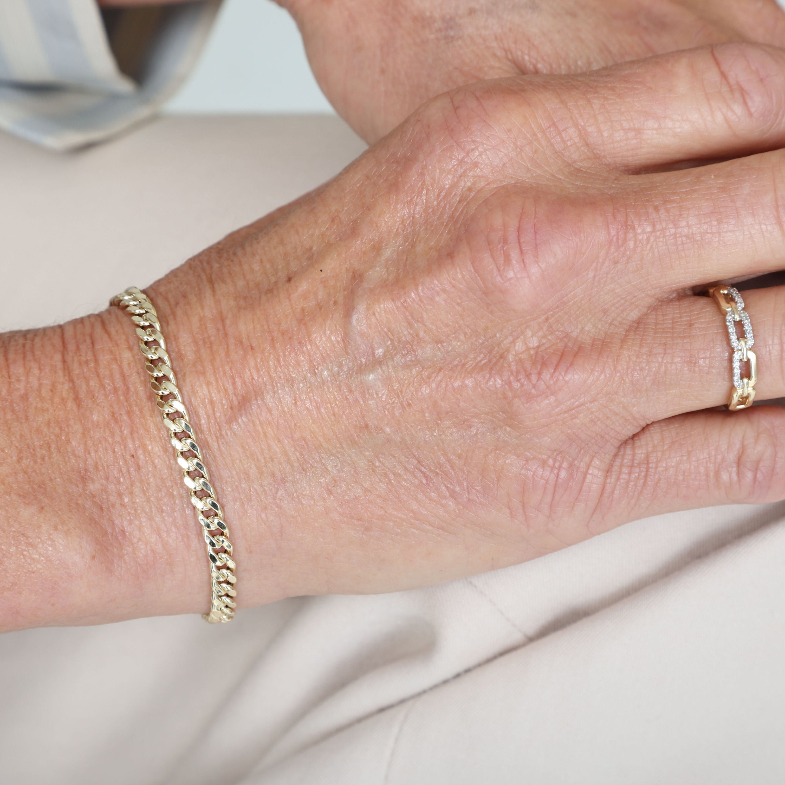 14K Gold Faceted Miami Cuban Link Bracelet worn with a professional outfit, providing a subtle yet stylish touch for work settings.