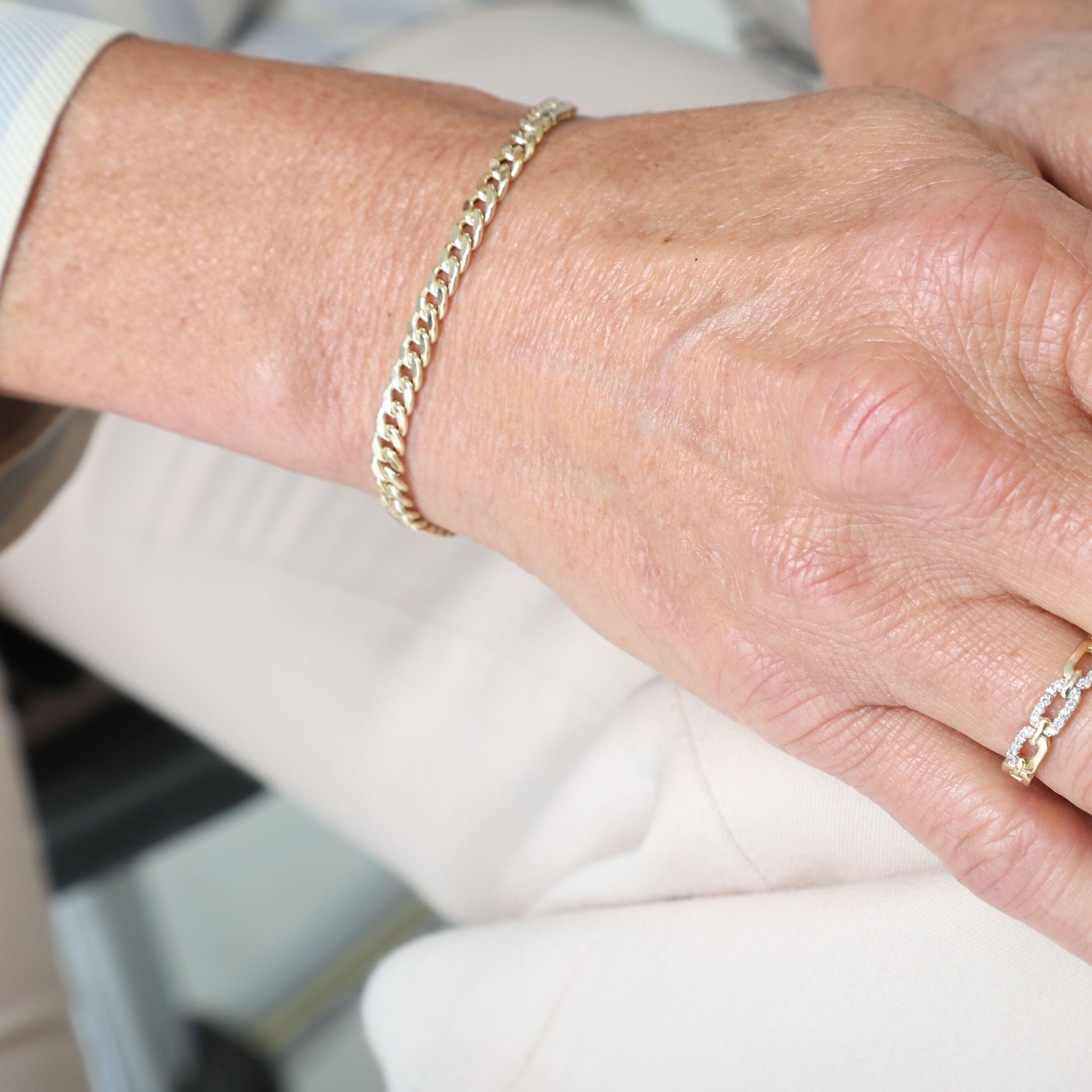14K Gold Faceted Miami Cuban Link Bracelet paired with white pants and neutral tones, offering a fresh and sophisticated casual look.