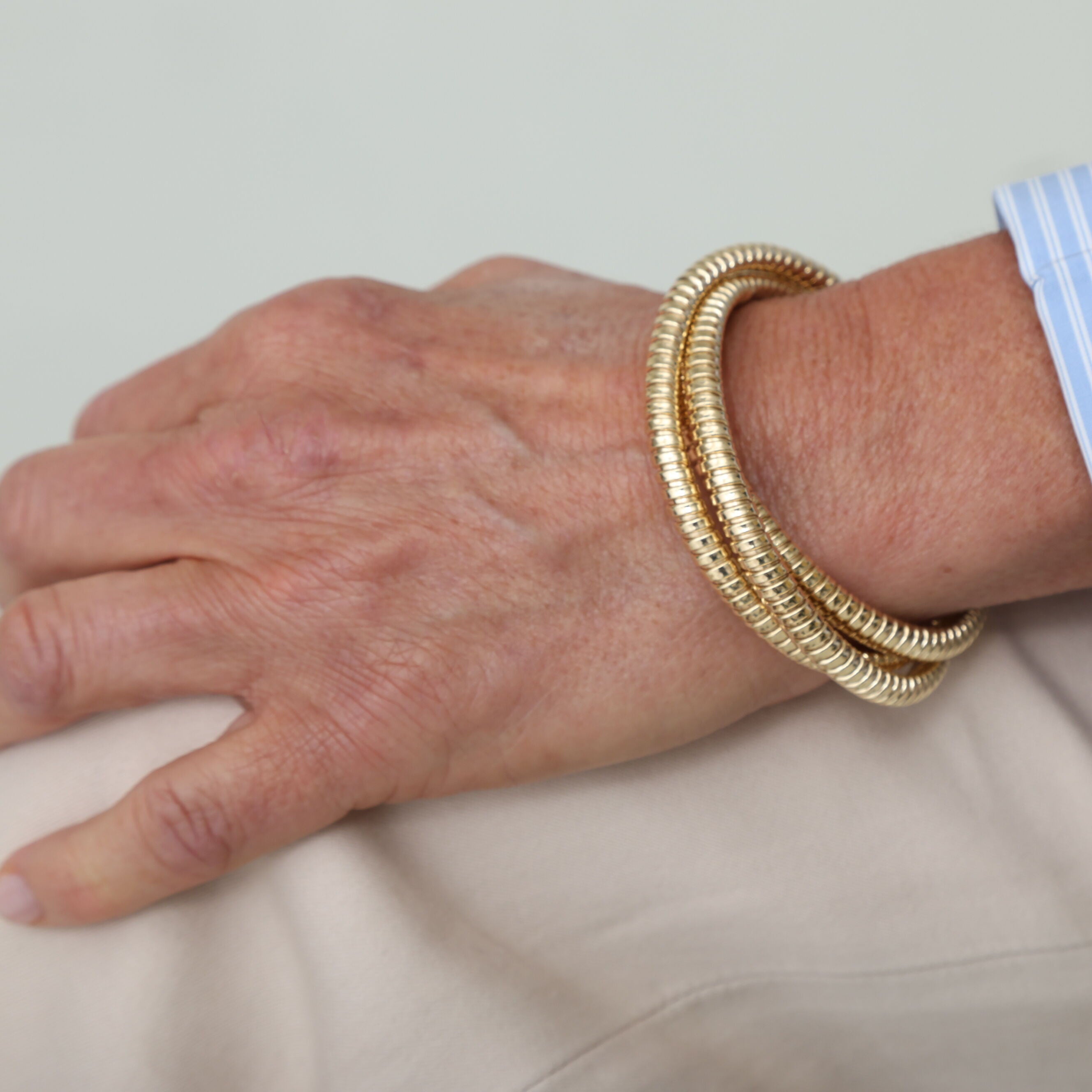 14K yellow gold Tubogas bangle worn with a beige outfit, complementing the warm tones for a refined yet understated style. Ideal for cocktail evenings, milestone celebrations, or stylish day-to-night wear.