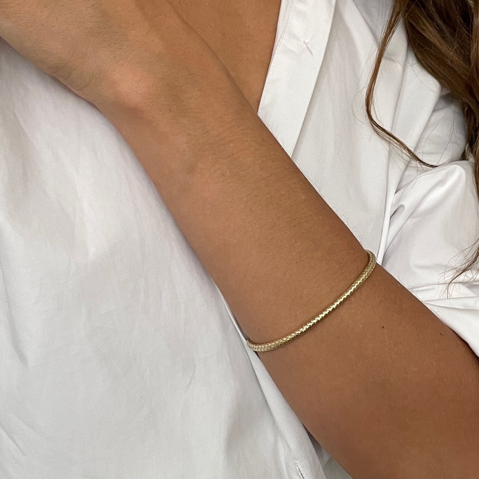 14K yellow gold woven bangle bracelet styled with layered gold pieces, creating a chic and textured wrist stack. A versatile look for dinner gatherings, anniversaries, or fashionable daily style.