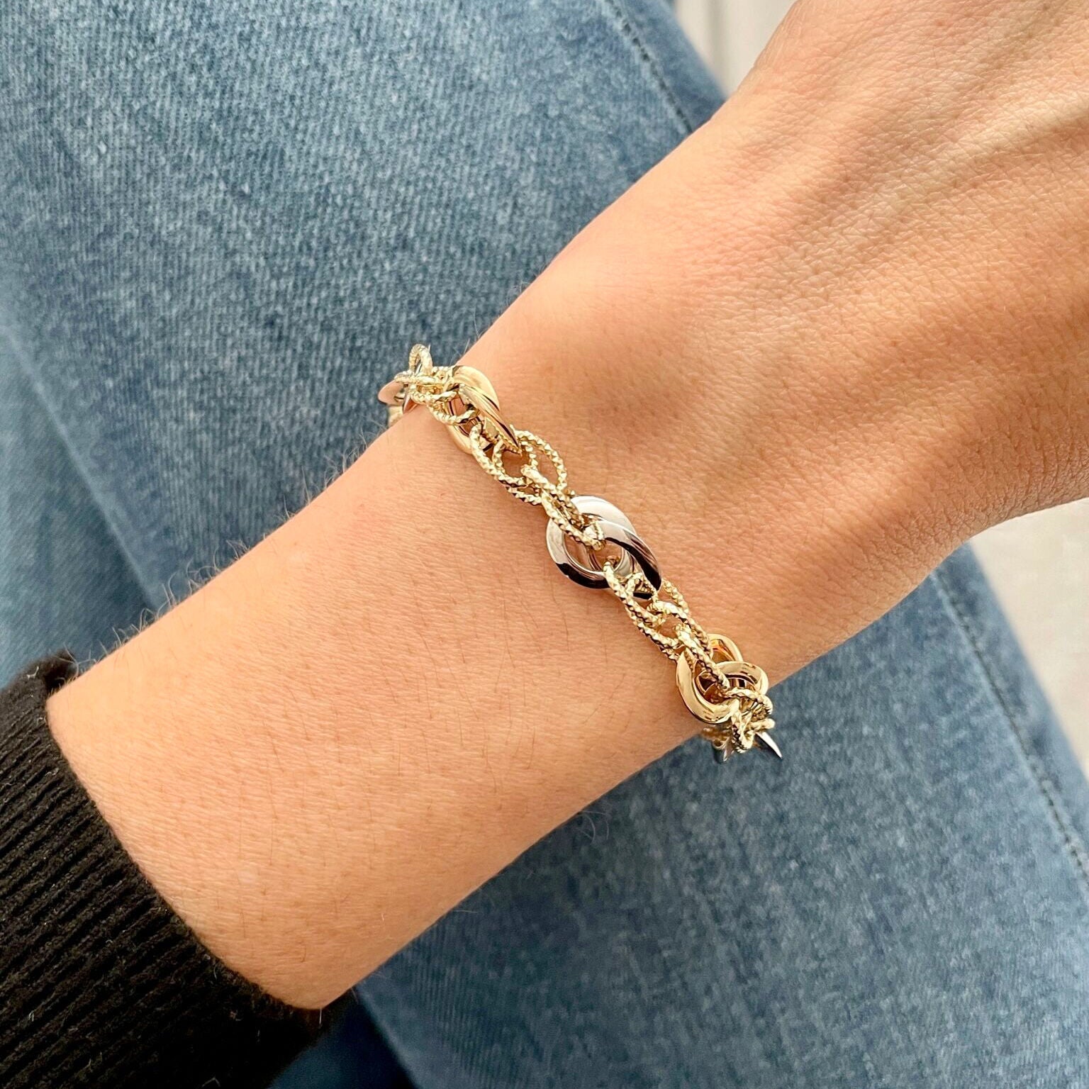 14K Two-Tone Gold Interlocking Links Bracelet styled with a black sweater and jeans, adding a sophisticated touch to casual wear for everyday elegance.