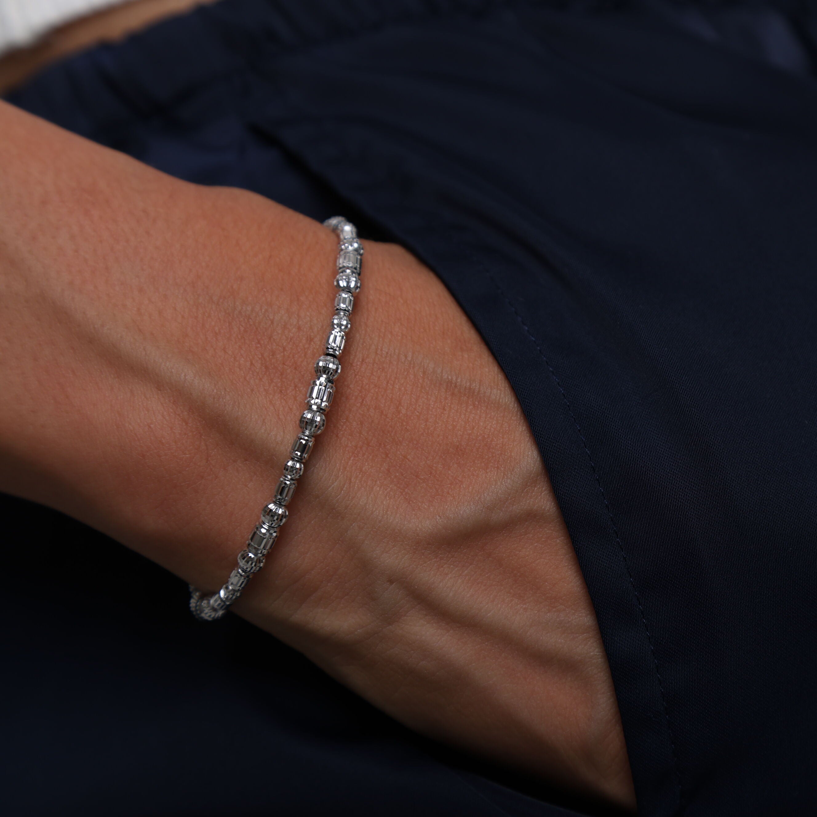 14K White Gold Barrel Bead Bracelet styled with a sleek black top, perfect for adding understated elegance and shine to evening wear.