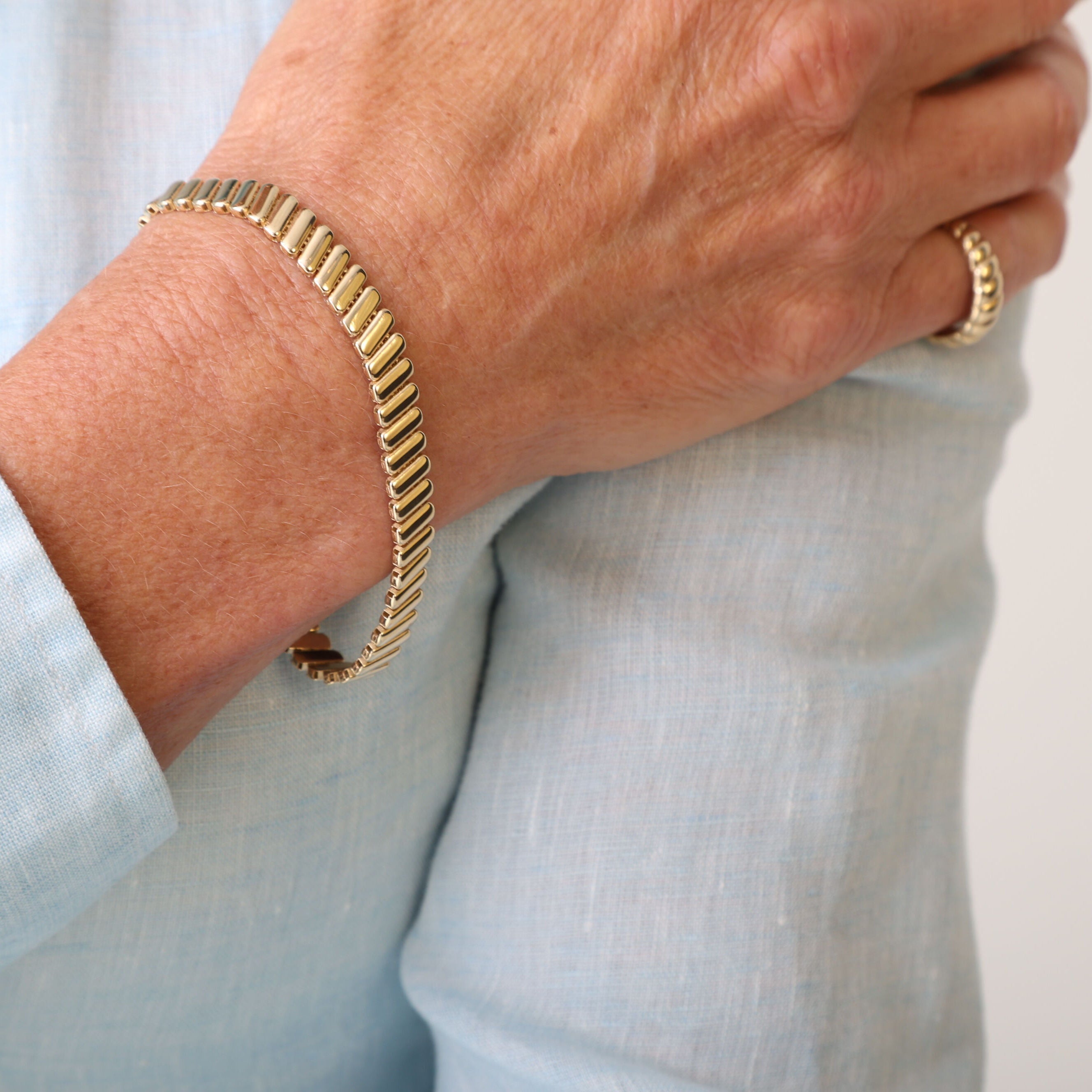 14K Yellow Gold Ribbed Bracelet styled with a light blue button-up shirt and matching gold necklace, perfect for professional events or casual daytime gatherings