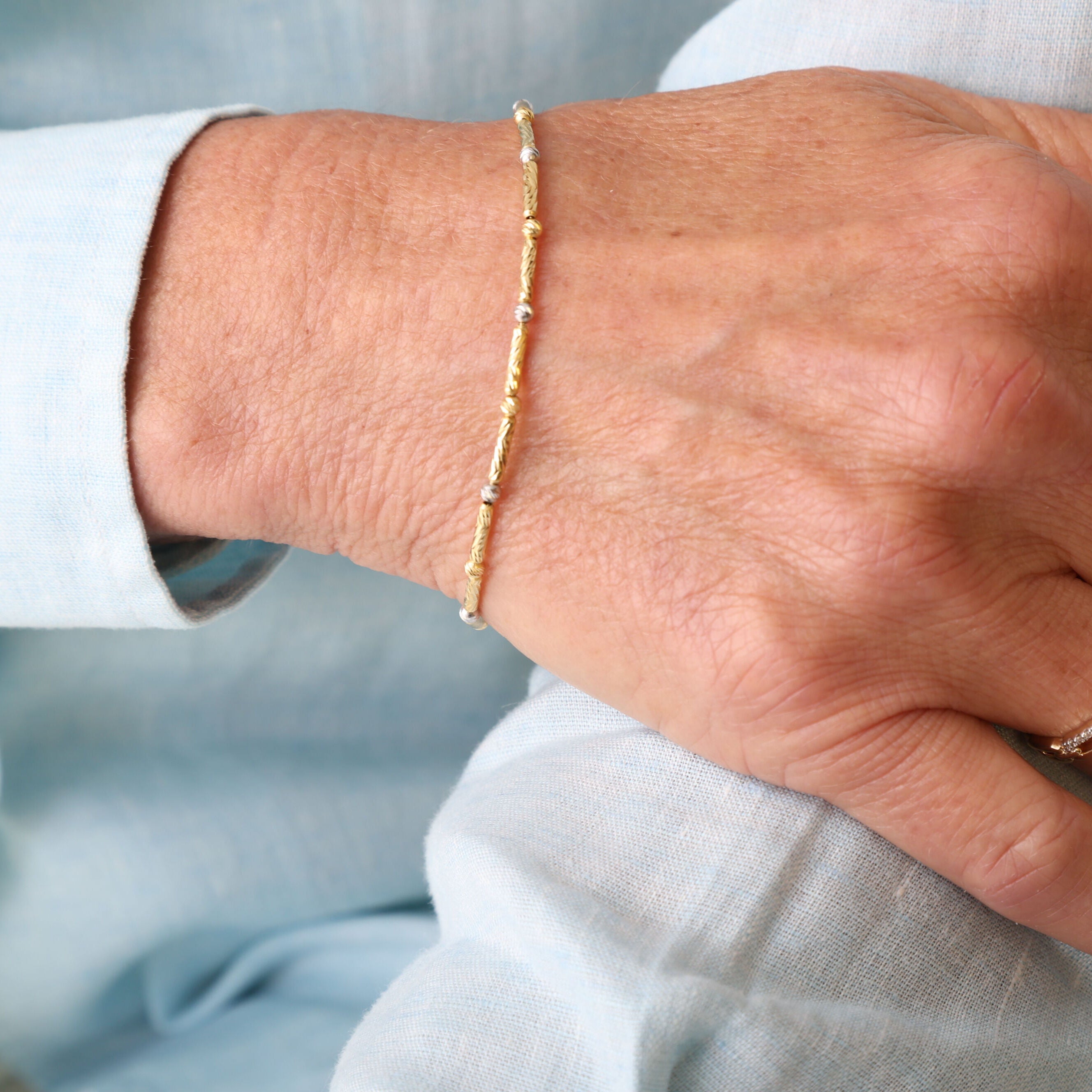 14K Two Tone Gold Bar and Bead Bracelet styled with light blue dress shirt and ivory trousers, perfect for a polished business casual look.
