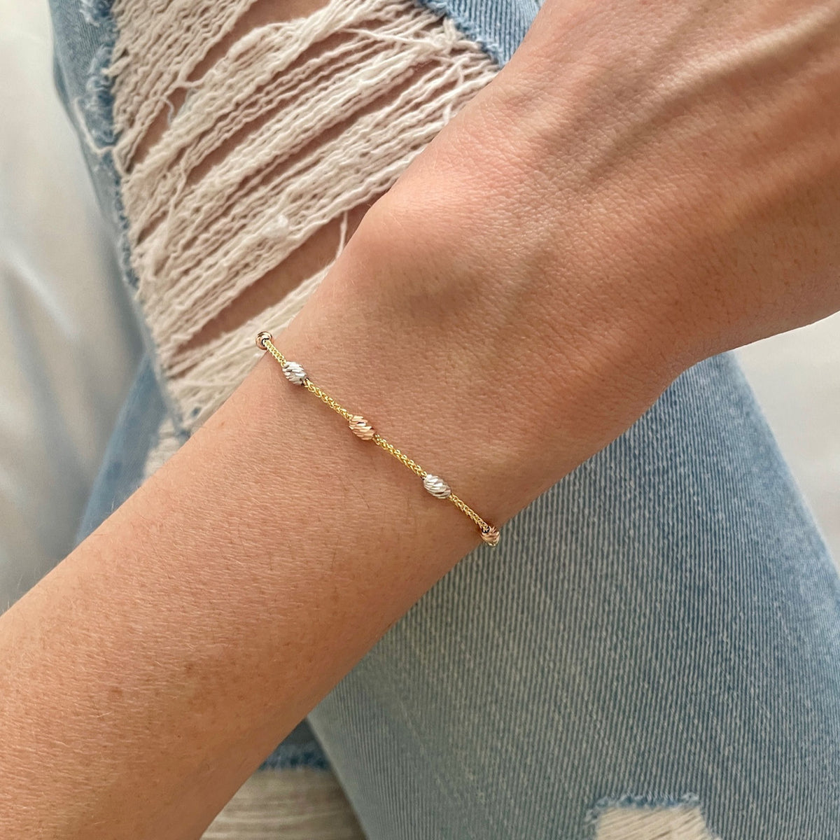 Close-up of 14K tricolor gold diamond-cut beaded friendship bracelet with adjustable 9.25" clasp