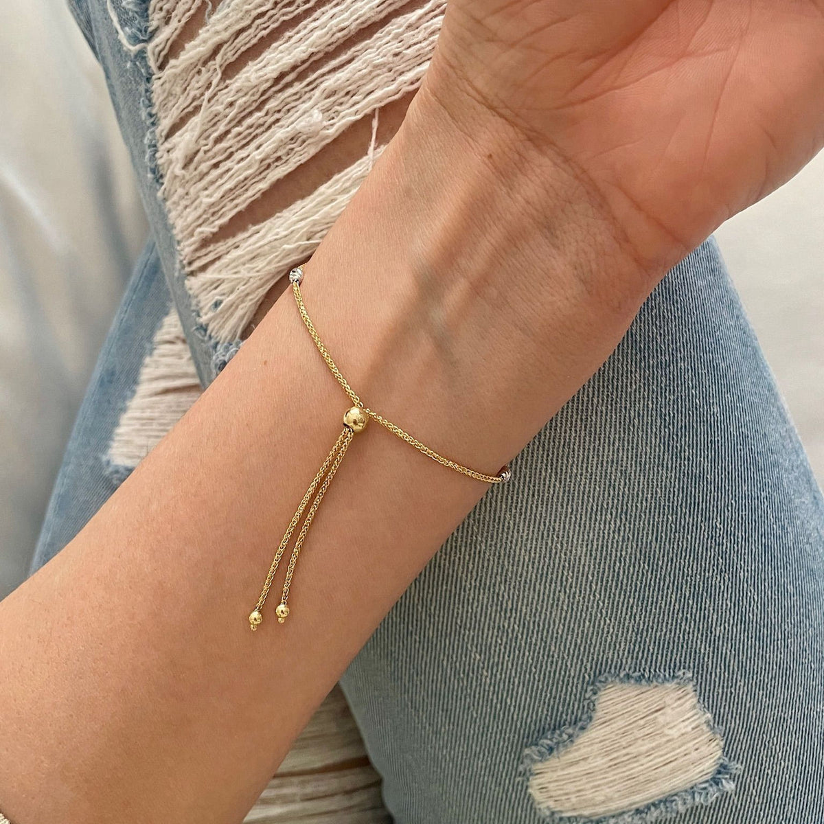 Styled wrist view of 14K tricolor gold diamond-cut beaded friendship bracelet with 9.25" adjustable length