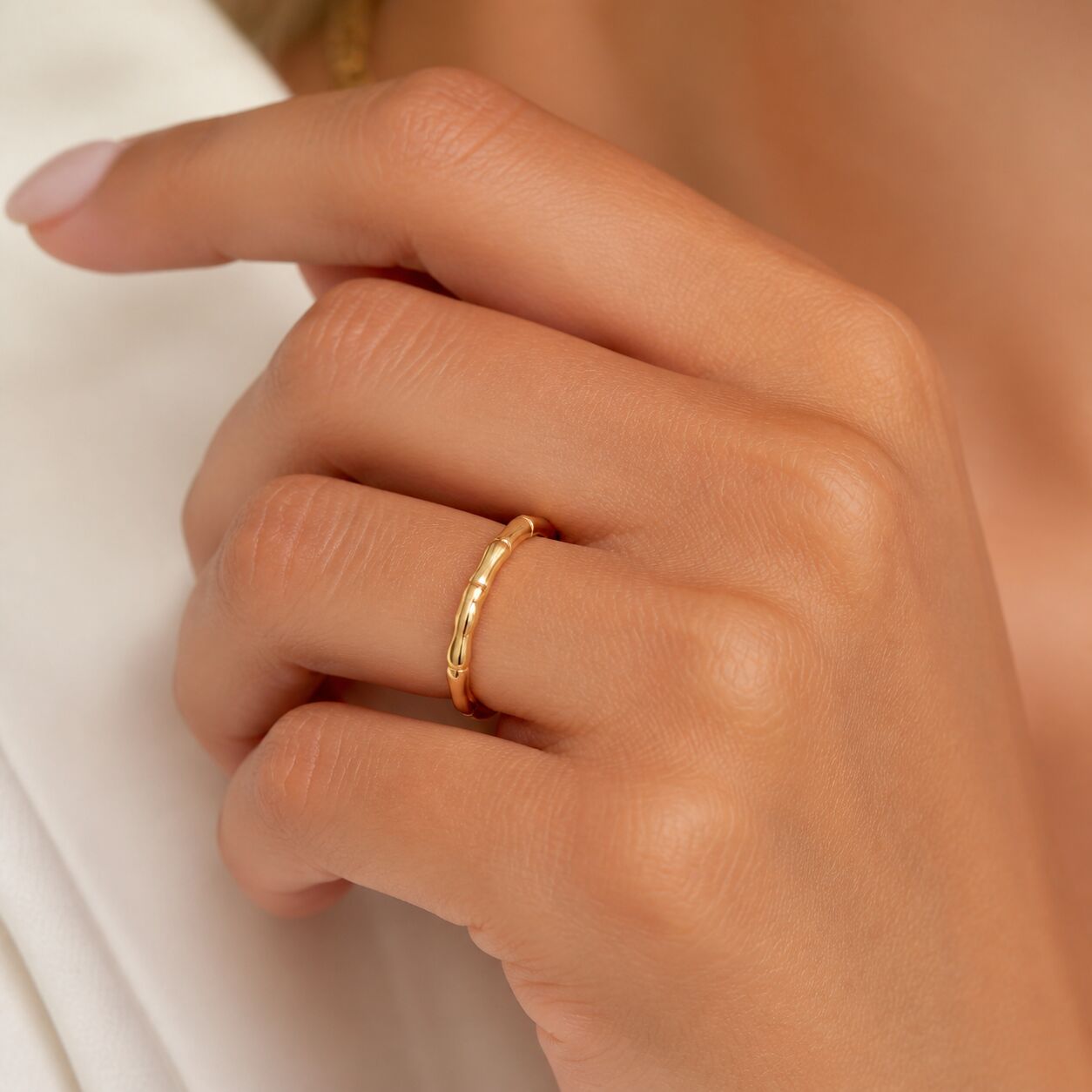 Close-up of 14K gold stackable band ring worn on finger with bamboo-inspired design