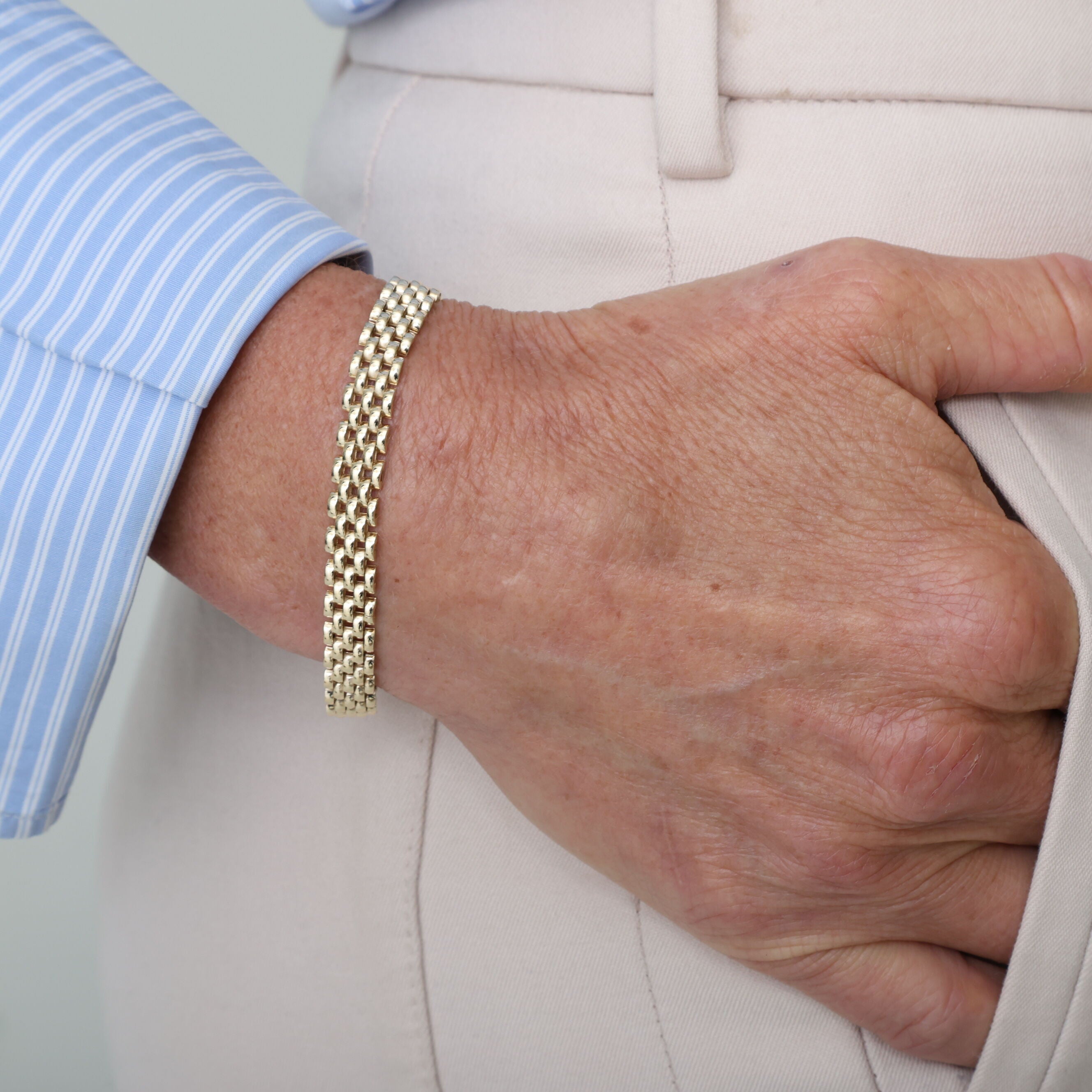 14K yellow gold Panther Link chain bracelet showcased on the wrist with a light pastel shirt. The versatile and timeless design adds understated elegance to casual or semi-formal looks, making it suitable for everyday wear, weekend outings, or dinner parties.