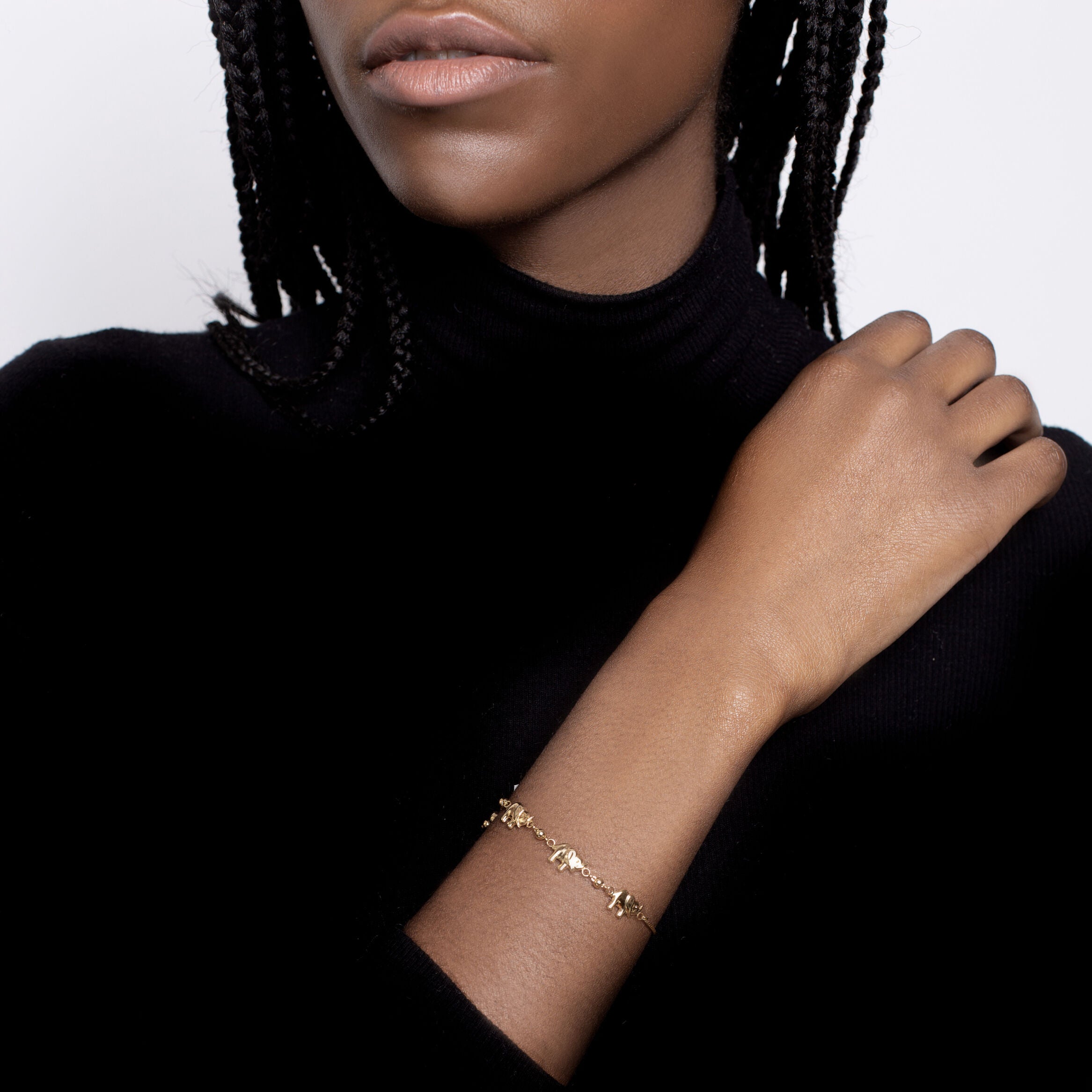 Adjustable 14K gold elephant charm friendship bracelet styled with a fitted black long-sleeve top. The delicate charm bracelet adds timeless sophistication and a subtle statement of loyalty and strength, ideal for anniversaries, milestone celebrations, or everyday chic wear.