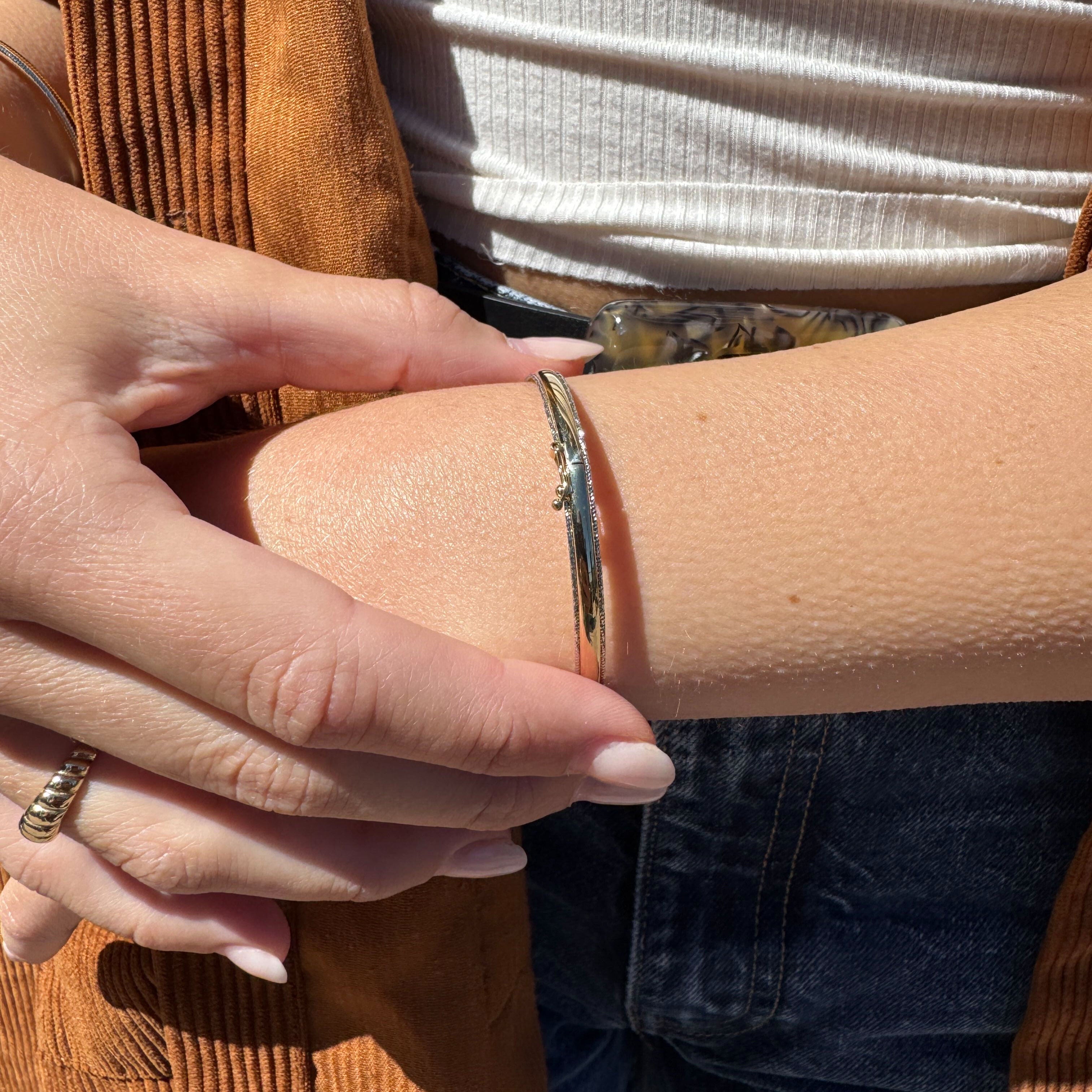14K two-tone glitter edge gold bangle bracelet worn on the wrist under natural sunlight, enhancing the outfit with a sparkling and timeless glow. A versatile accessory for casual meetings, brunch, or day outings.