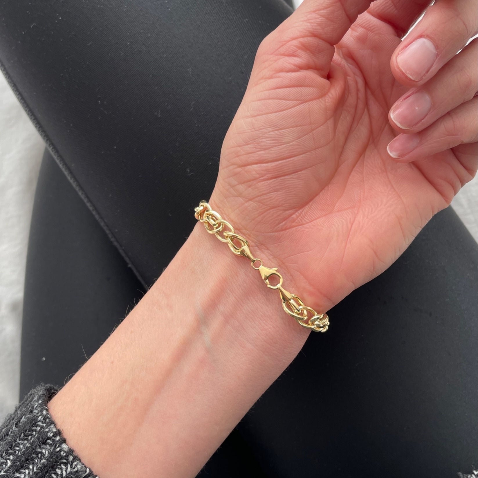 Yellow gold oval link bracelet styled with a soft knit sweater. The warm polished gold enhances the cozy, relaxed outfit with a touch of refined elegance. Ideal for everyday wear, weekend outings, or casual gatherings with friends.