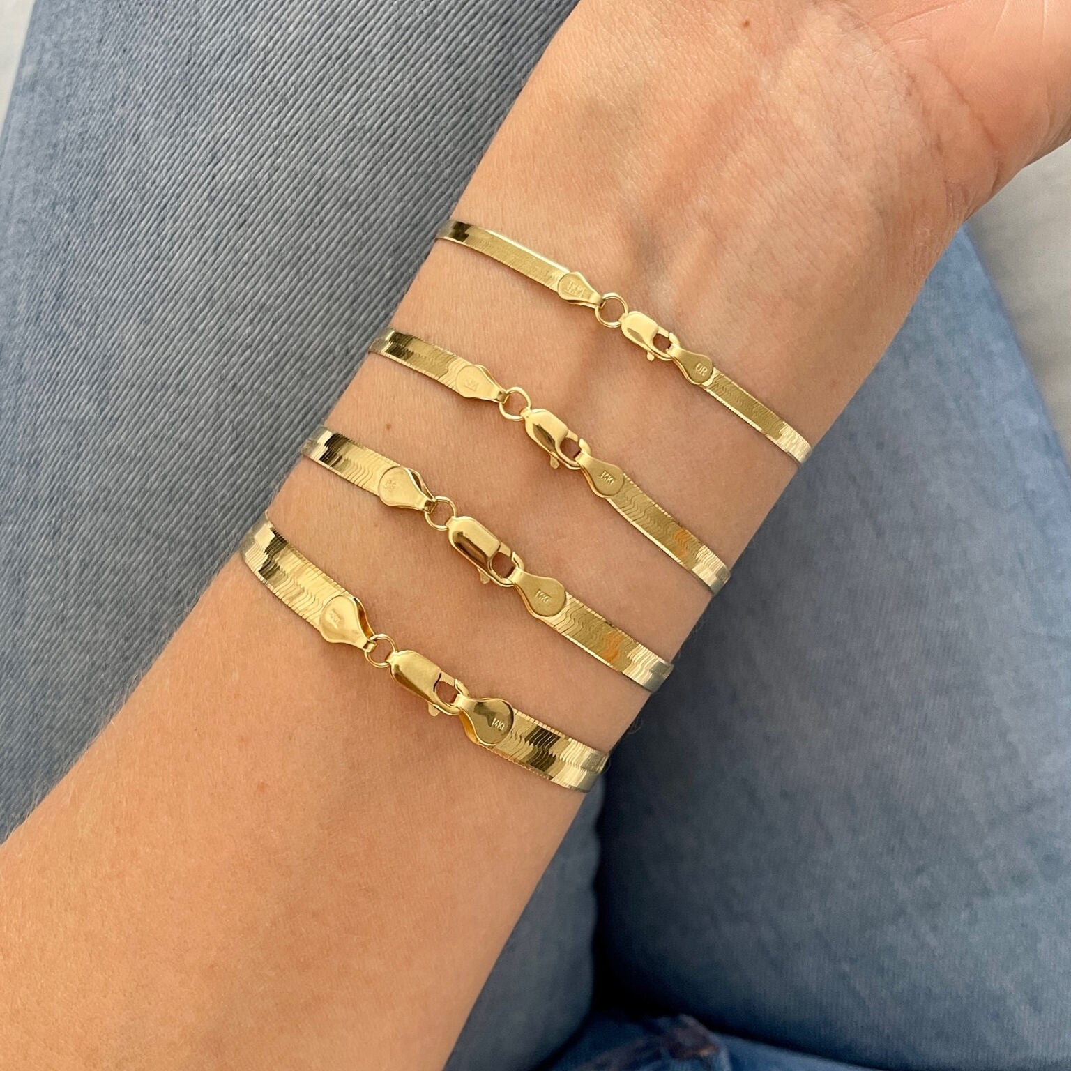 Yellow gold herringbone bracelet worn on the wrist with a relaxed knit outfit. The mirror-polished surface adds sleek sophistication while keeping the style minimal and refined. Ideal for workdays, anniversary dinners, or effortless luxury in daily wear.