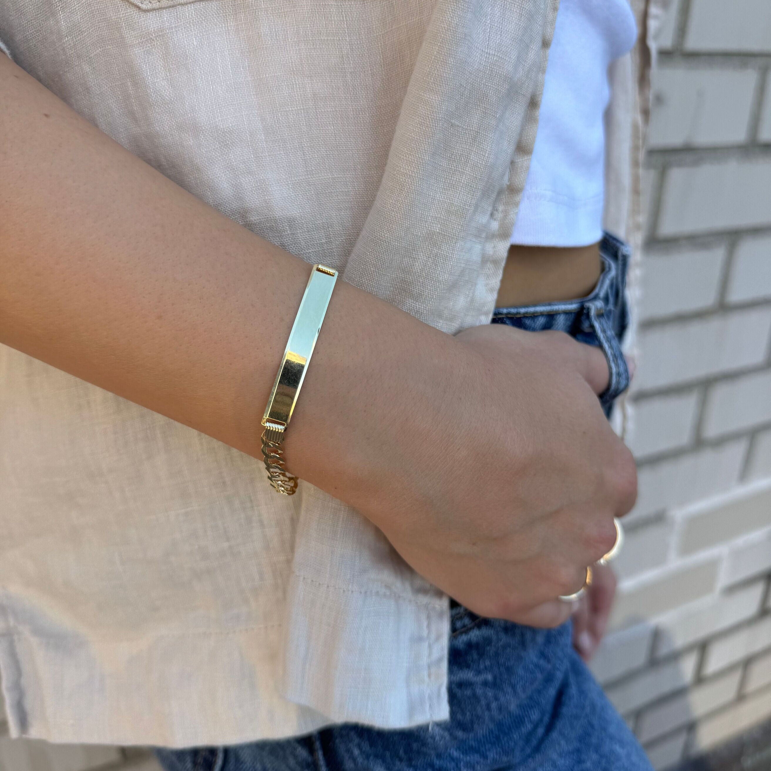 Yellow gold ID bar curb link bracelet paired with a light blue denim jacket and casual wear. The bold chain links add confidence and style while the engravable bar offers a personalized touch. Perfect for everyday wear, casual meetings, or stylish day events.