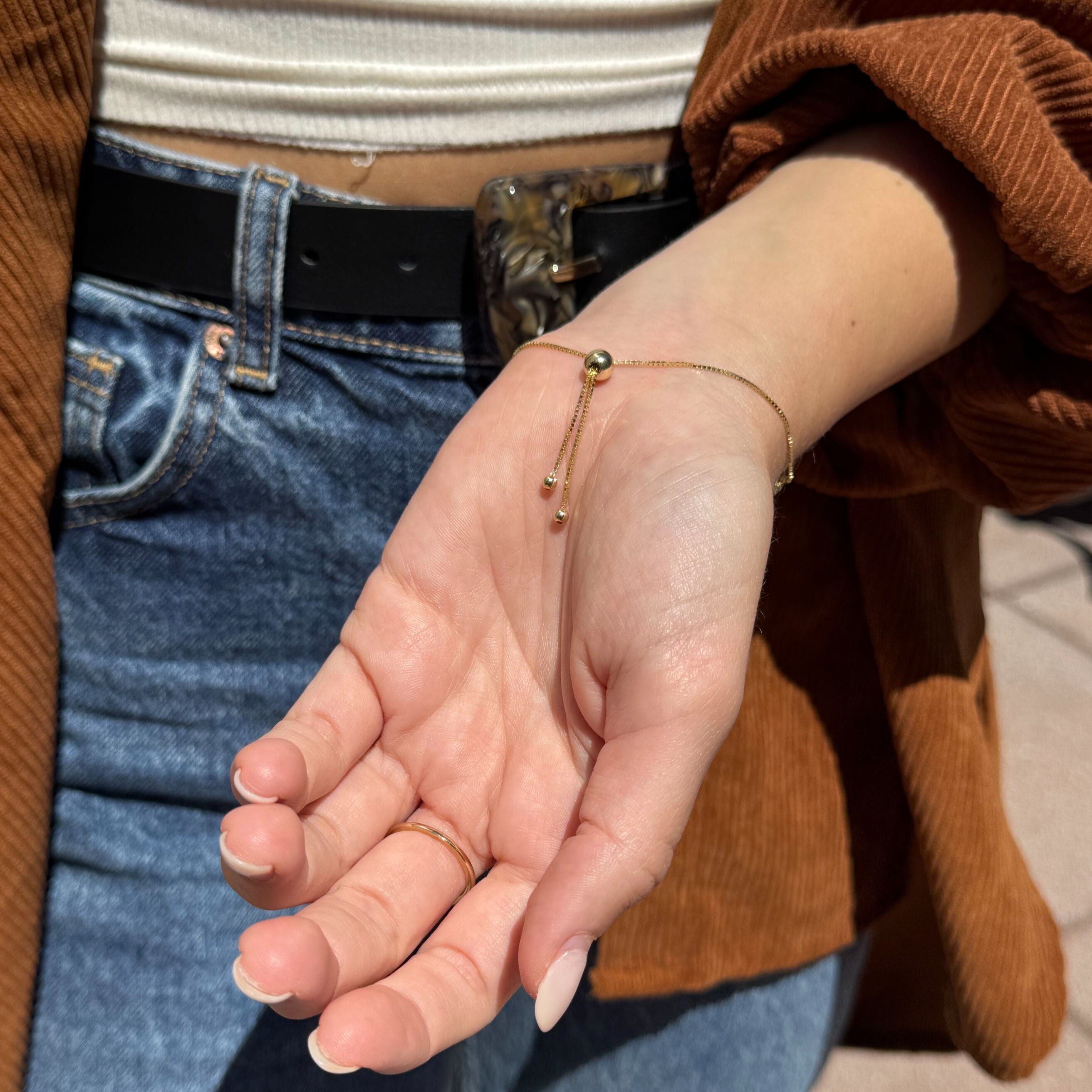 14K Gold Friendship Bracelet layered with gold rings, styled for timeless feminine charm and casual grace