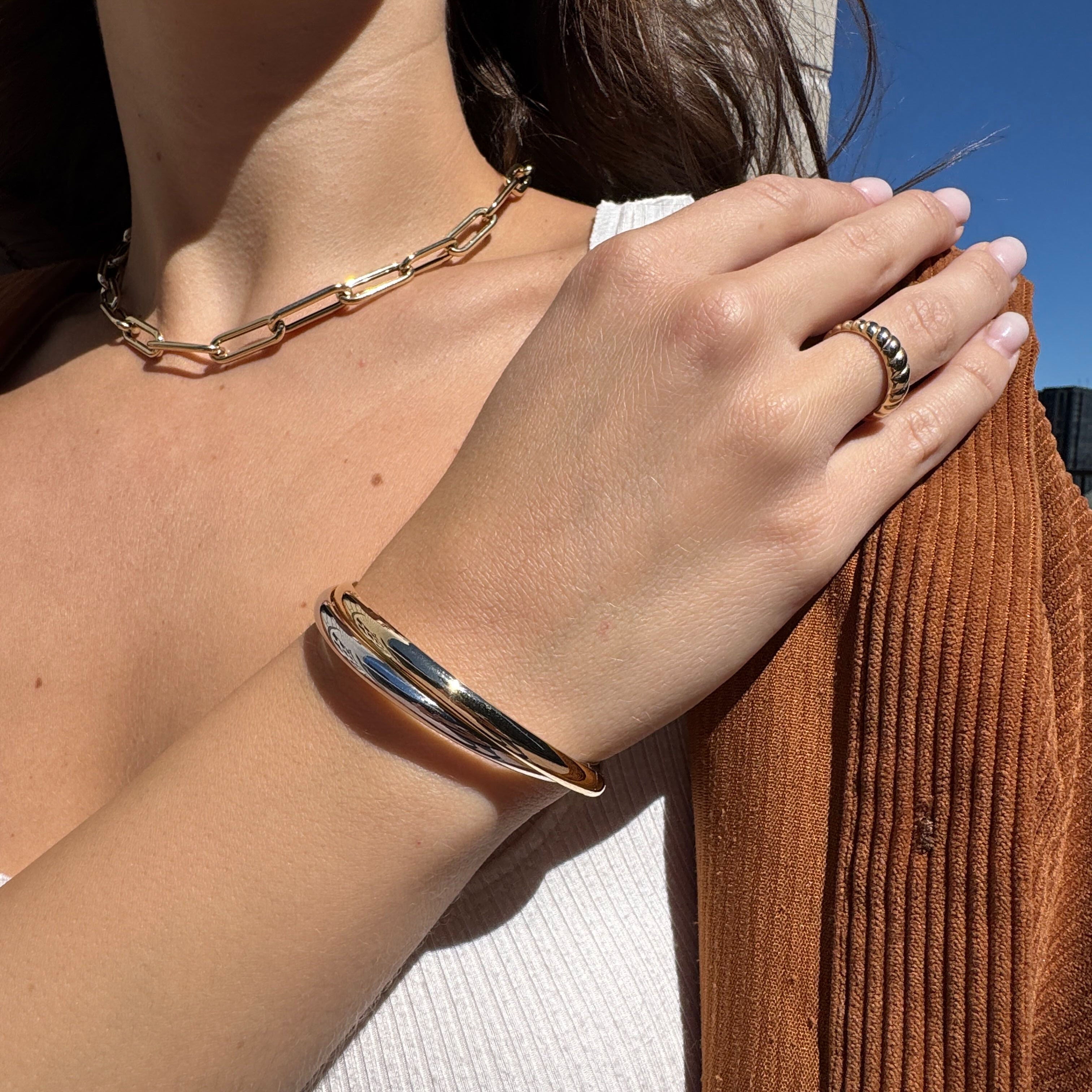 The bold crossover bangle brings dimension to an outfit featuring layered rings and warm textures, an ideal accessory for work to weekend style.