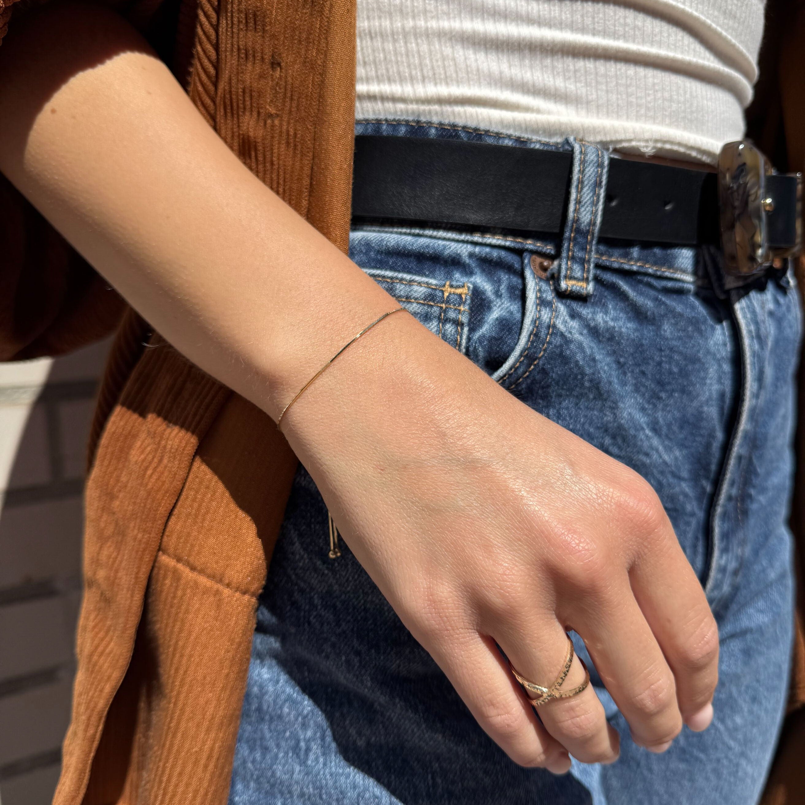 14K Gold Heart Bracelet styled with other gold rings and no other bracelets, making it ideal for a focused, feminine wrist stack look
