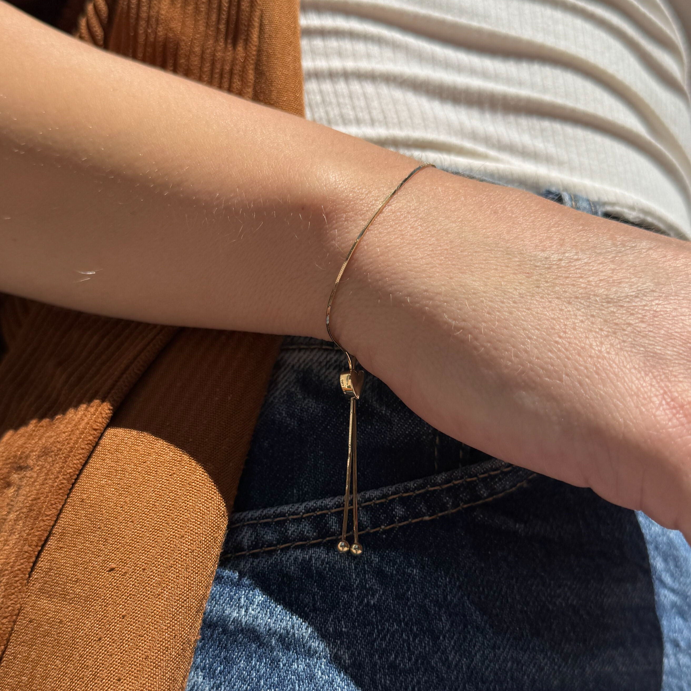 Gold Friendship Bracelet styled alone on a bare wrist with soft neutral fabrics, ideal for feminine casualwear or understated gifting aesthetics
