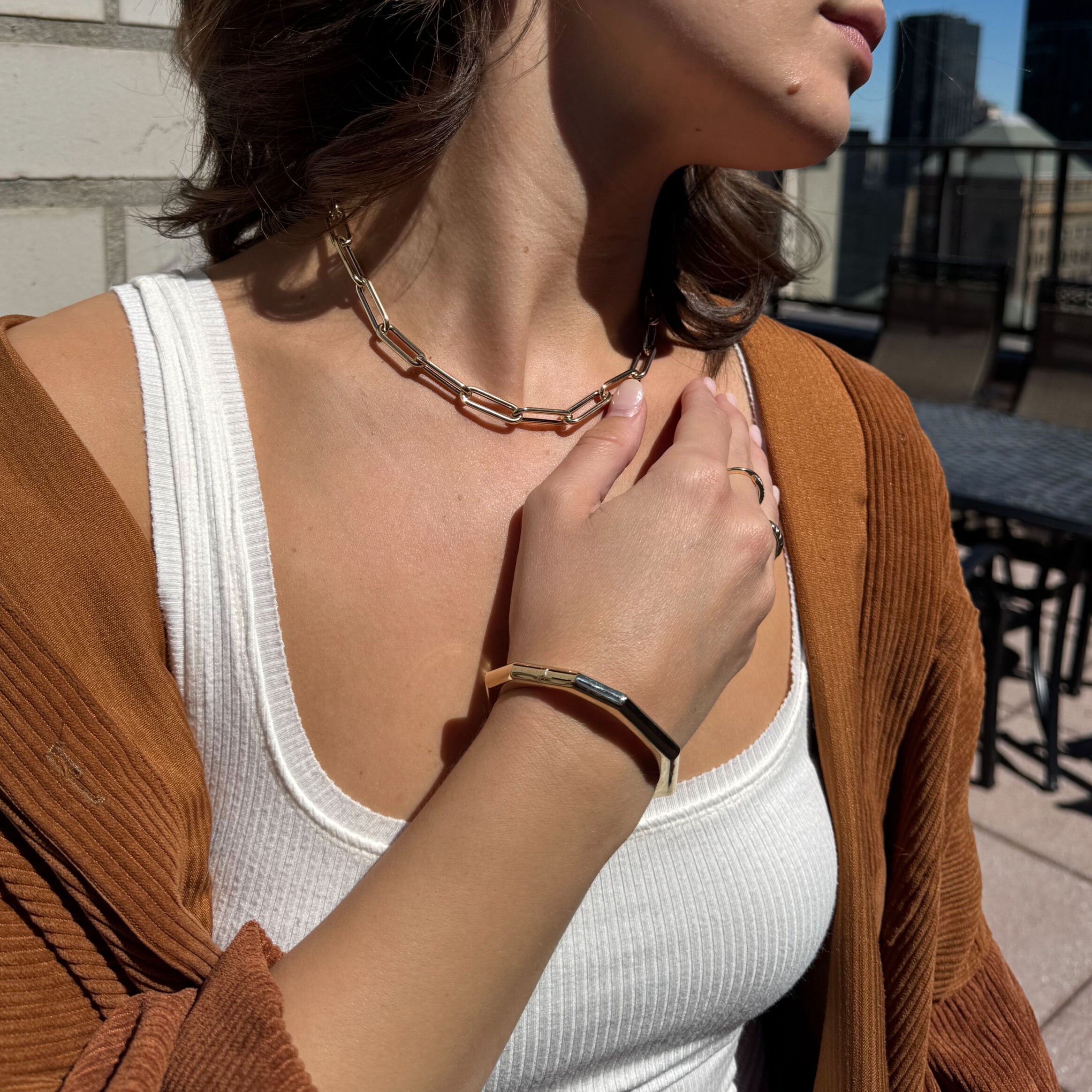 Styled with a square neckline and simple layers, this sculptural gold bangle becomes a bold highlight for casual yet elevated outfit pairings.