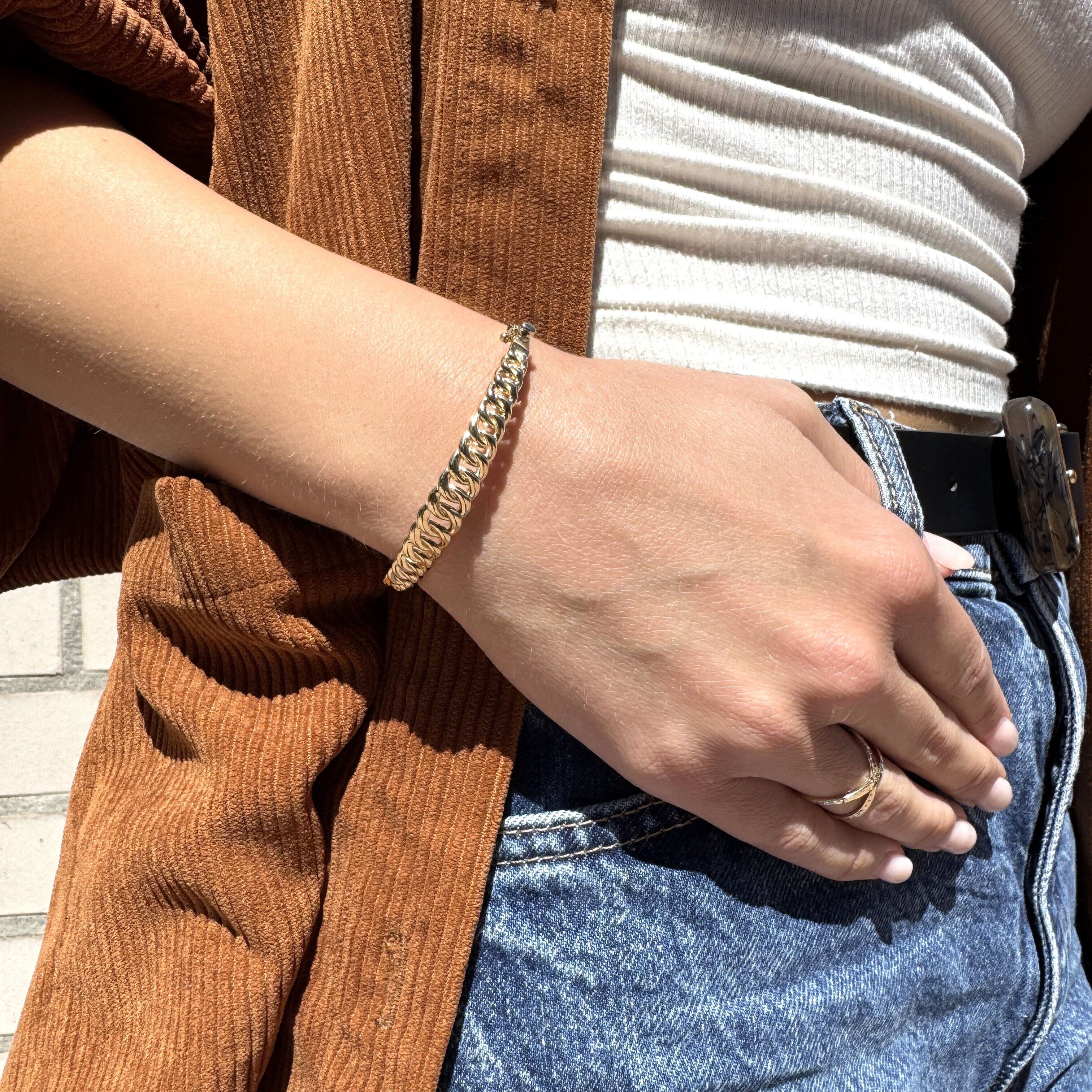 Styled with a white ribbed tank and autumn tones, this curb bangle shines against textured layers for a curated statement wrist stack.