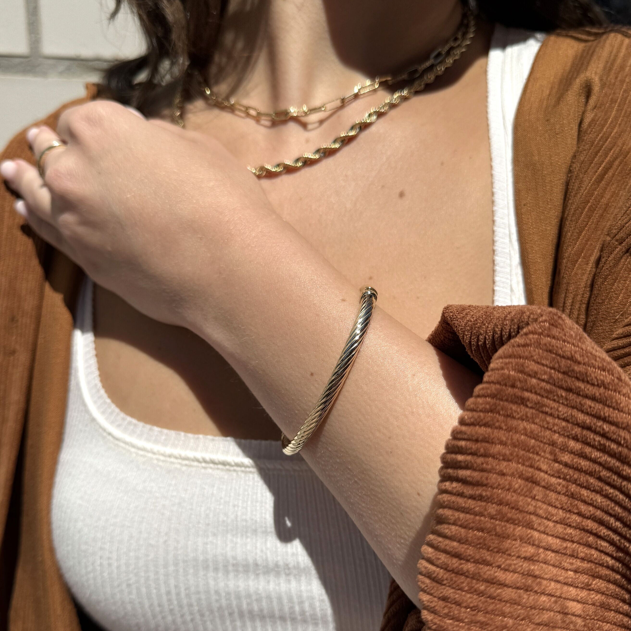 Layered with gold rings and a ribbed cami, this twist rope bangle in 14K gold finishes the look with timeless edge, ideal for weekend styling or casual Fridays.