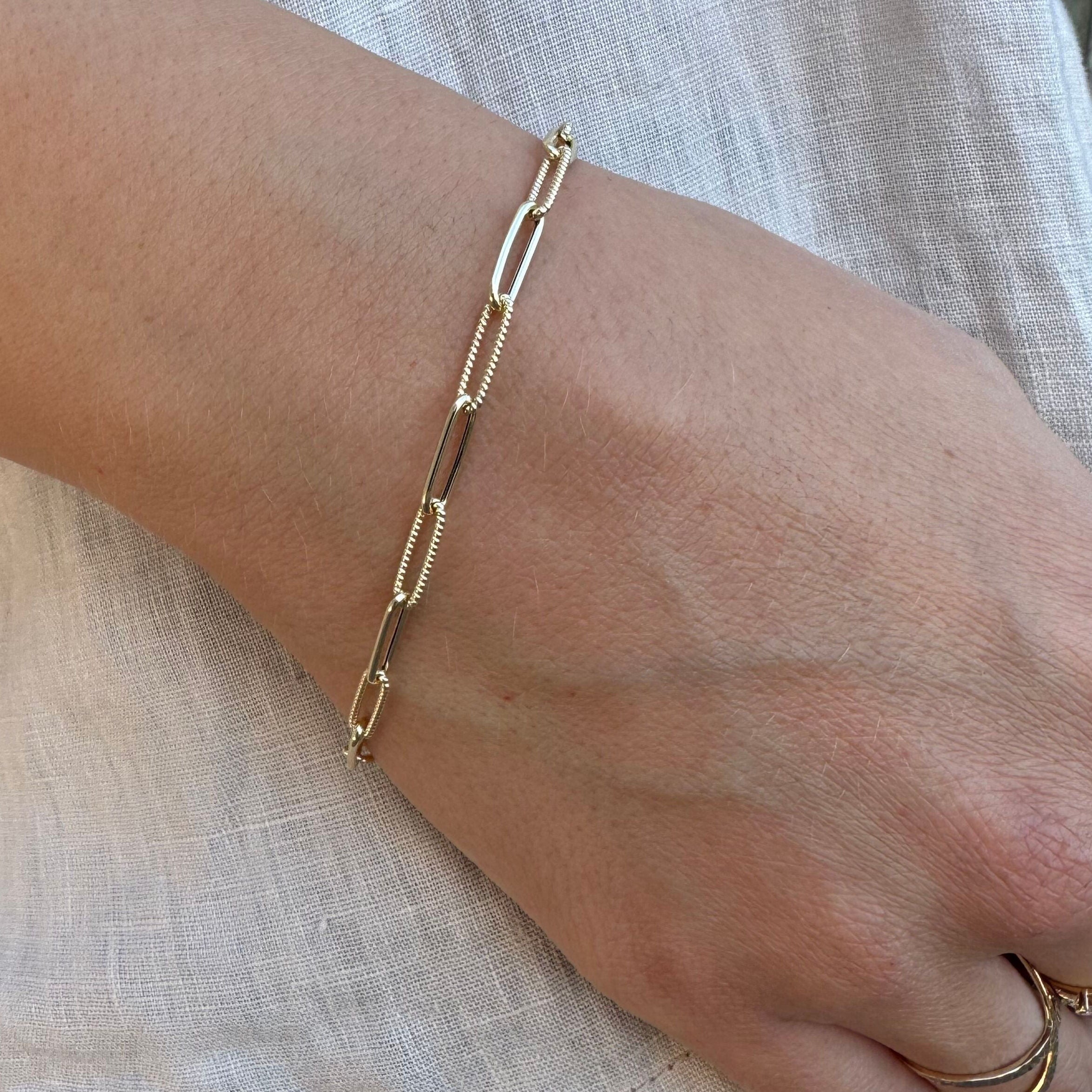 14K Gold Paperclip Chain Bracelet styled with a white tee and beige shirt, adding a touch of elegance and confidence to a casual look. Perfect for everyday wear, workdays, and coffee meetups.