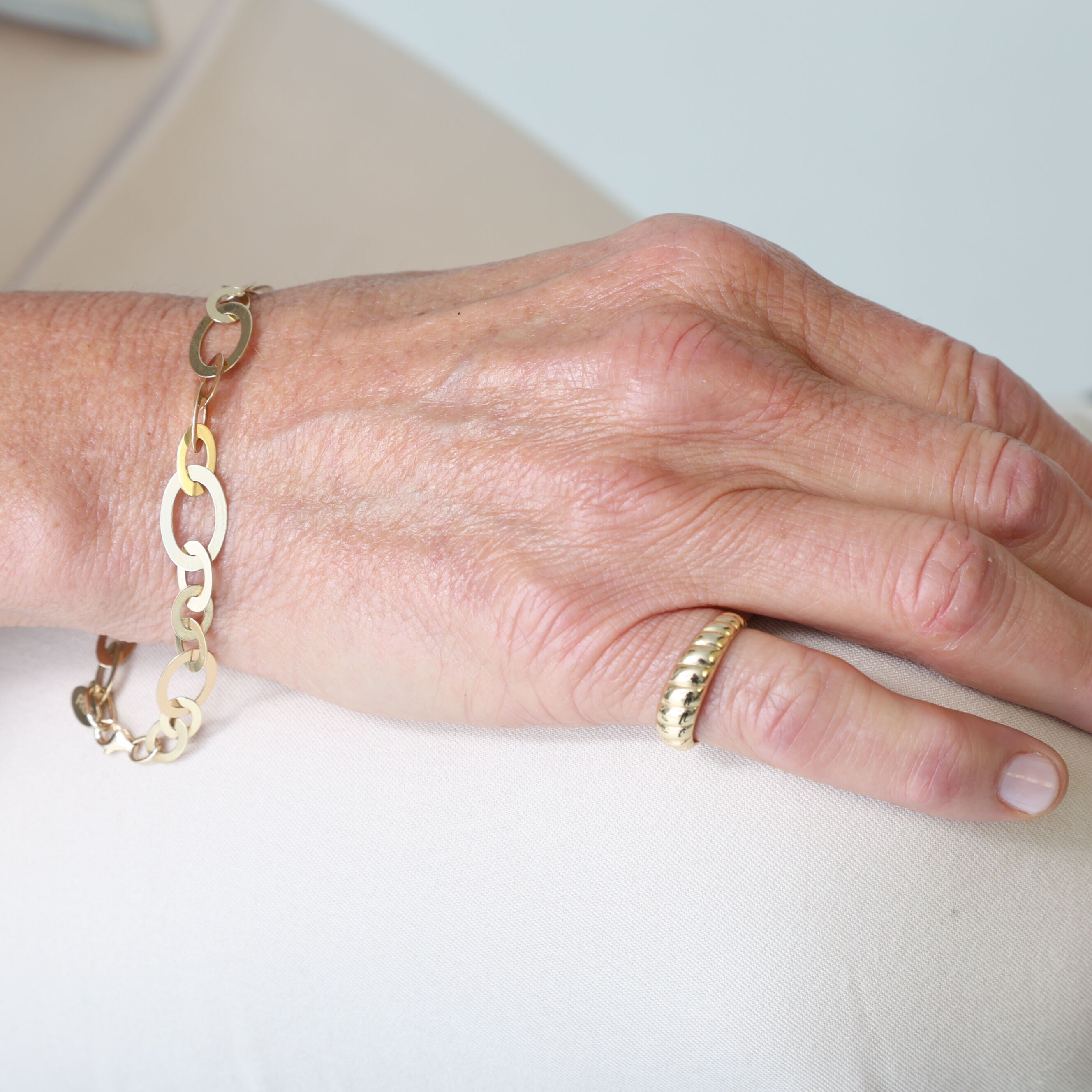 14K Gold Flat Oval Bracelet worn with a striped blouse and soft waves hairstyle, perfect for semi-formal gatherings or client lunches