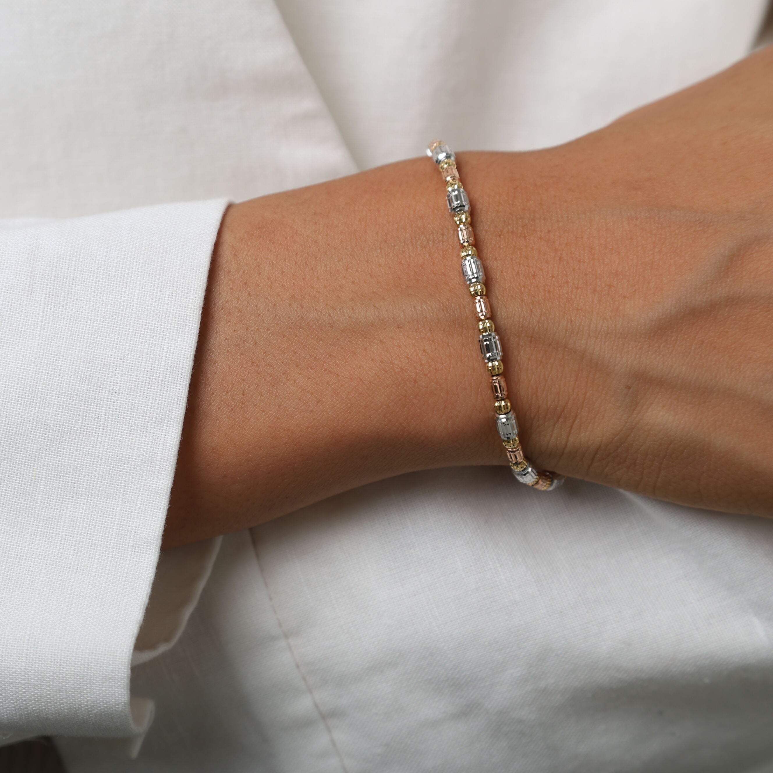 14K Tricolor Gold Barrel Bead Bracelet paired with a soft light sweater, creating a cozy yet refined look ideal for relaxed social gatherings.