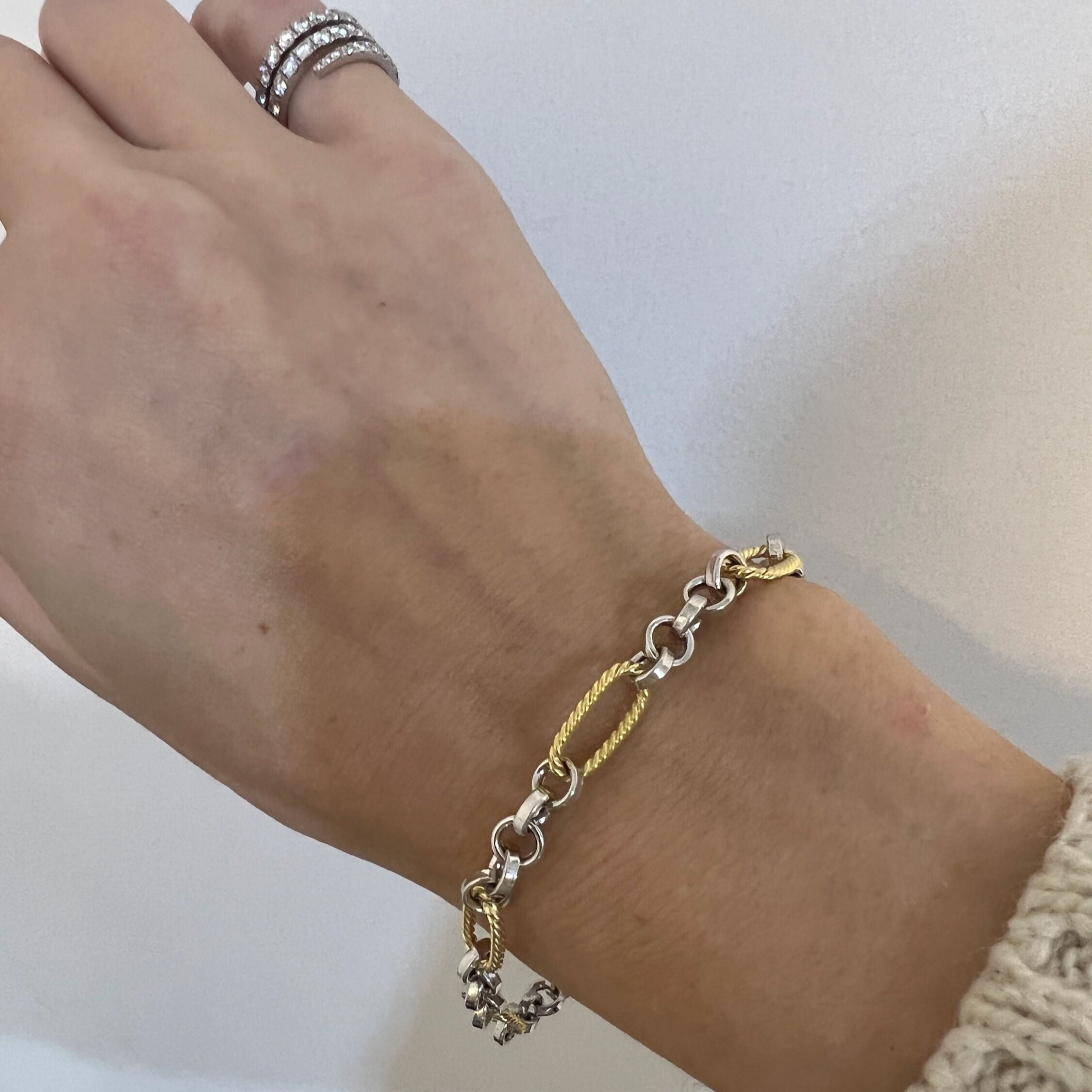 14K two tone gold oval and round link bracelet worn on the wrist with a cream knit sweater and diamond rings. The mix of white and yellow gold adds refined contrast, enhancing the outfit’s polished and elegant look. Perfect for anniversaries, dinners, or everyday luxury style.