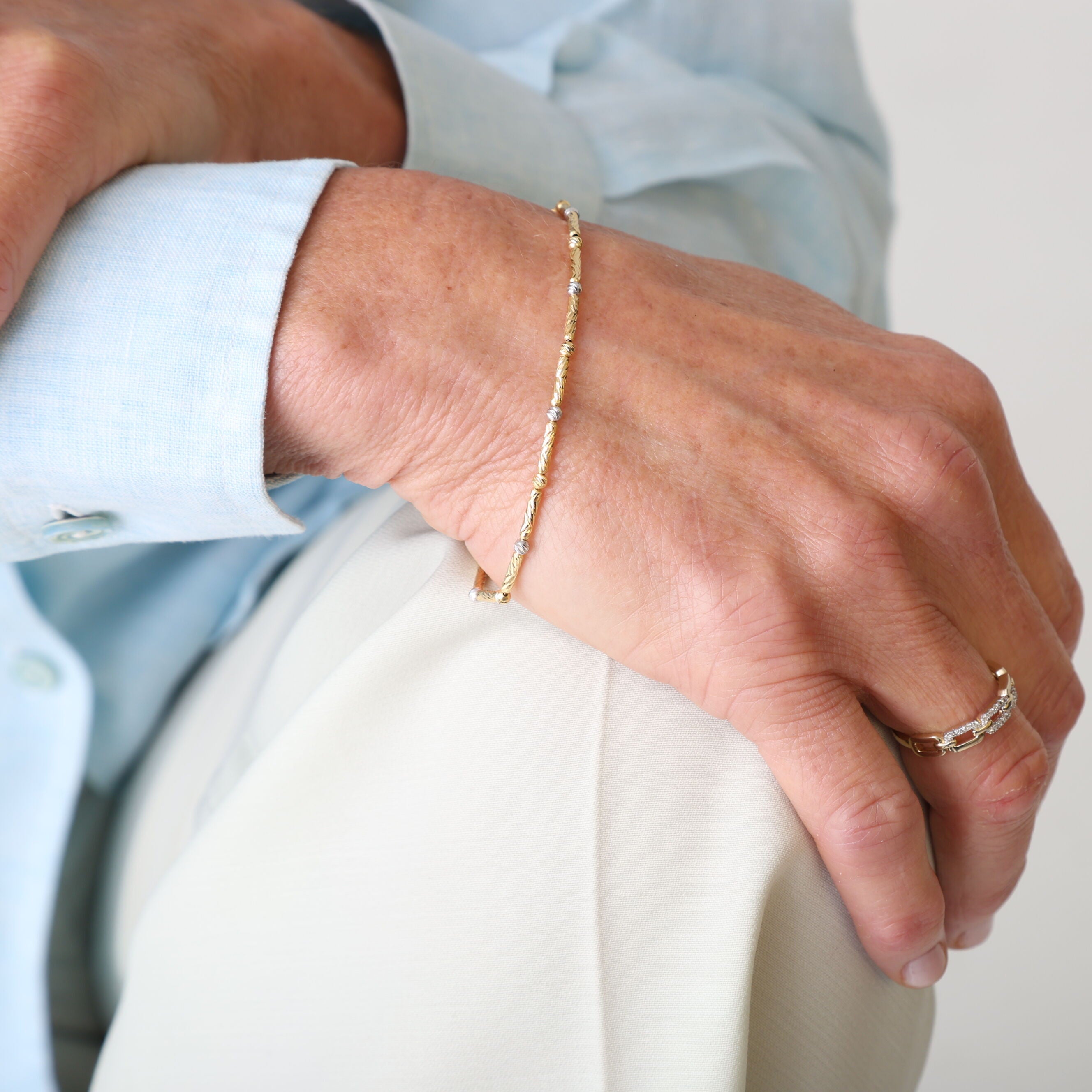 14K Two Tone Gold Bar and Bead Bracelet worn with pastel button-down and beige pants, perfect for a relaxed day gathering or weekend brunch.