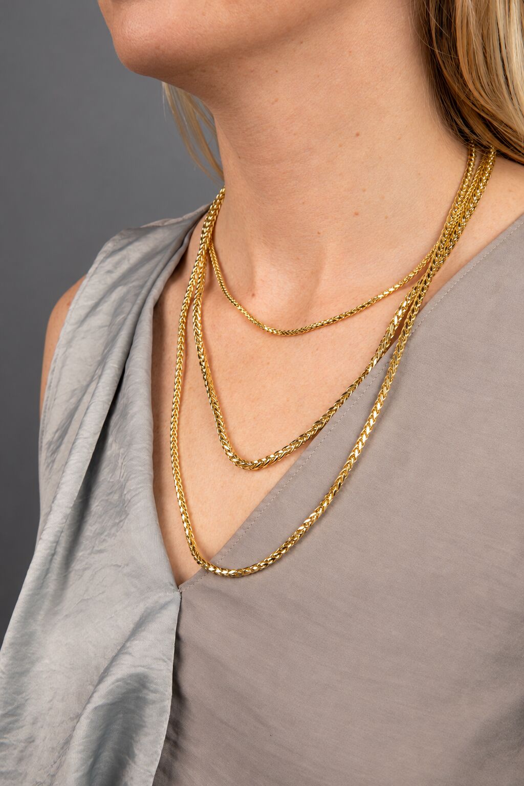 14K yellow gold round wheat chain necklace with diamond-cut finish draped on white jewelry bust