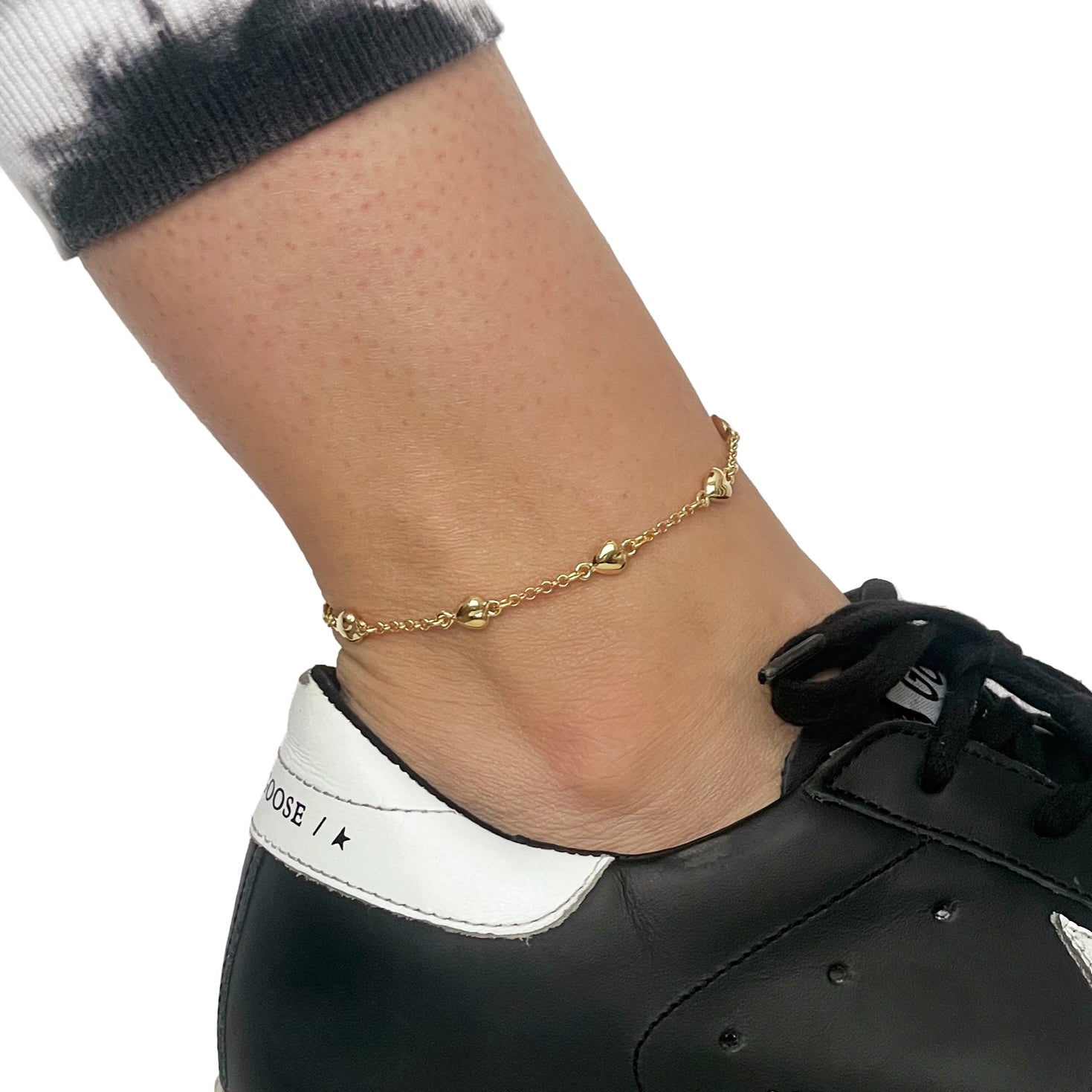 14k yellow gold puffed heart station anklet on a woman's ankle