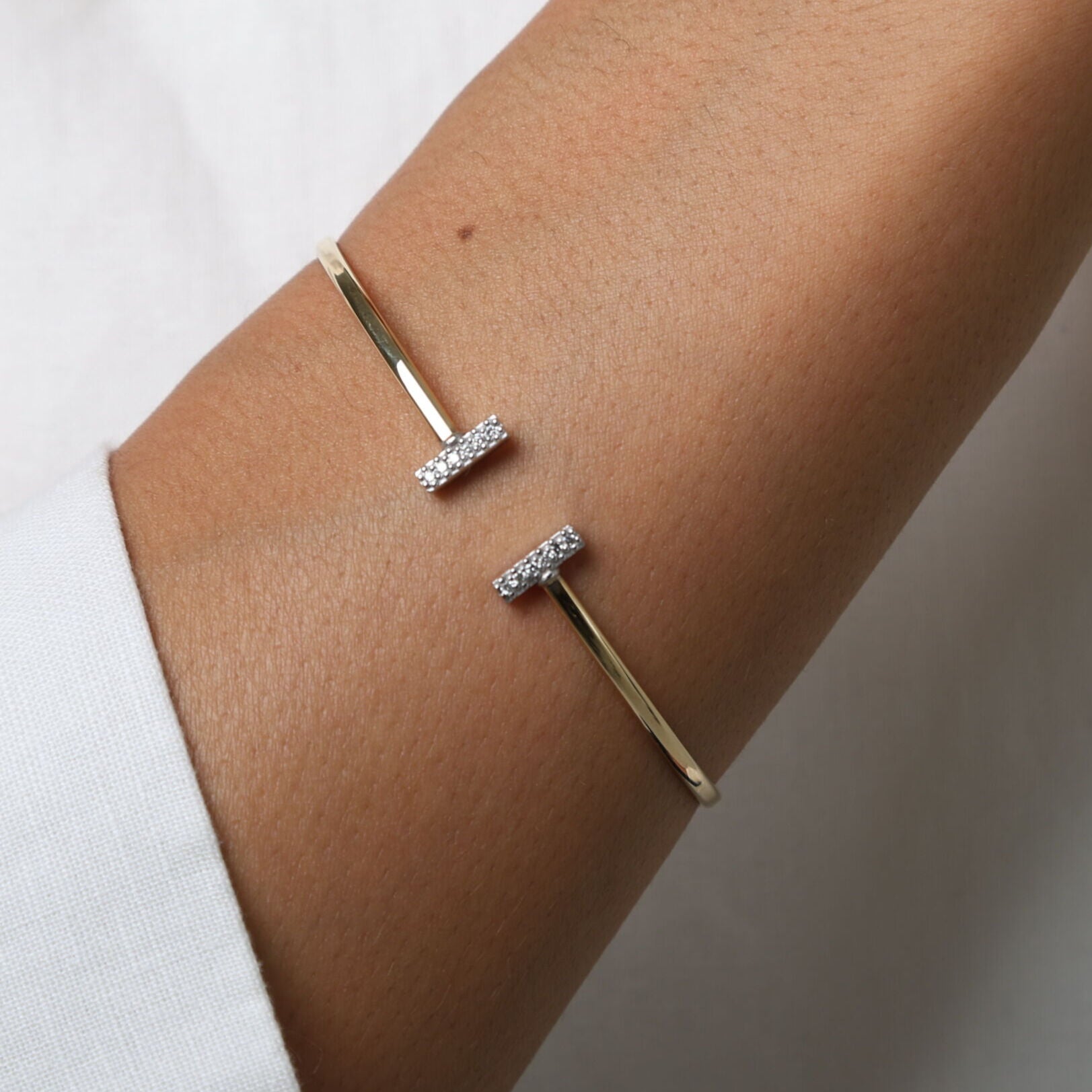 Gold bracelet with small diamonds on a wrist against a white background