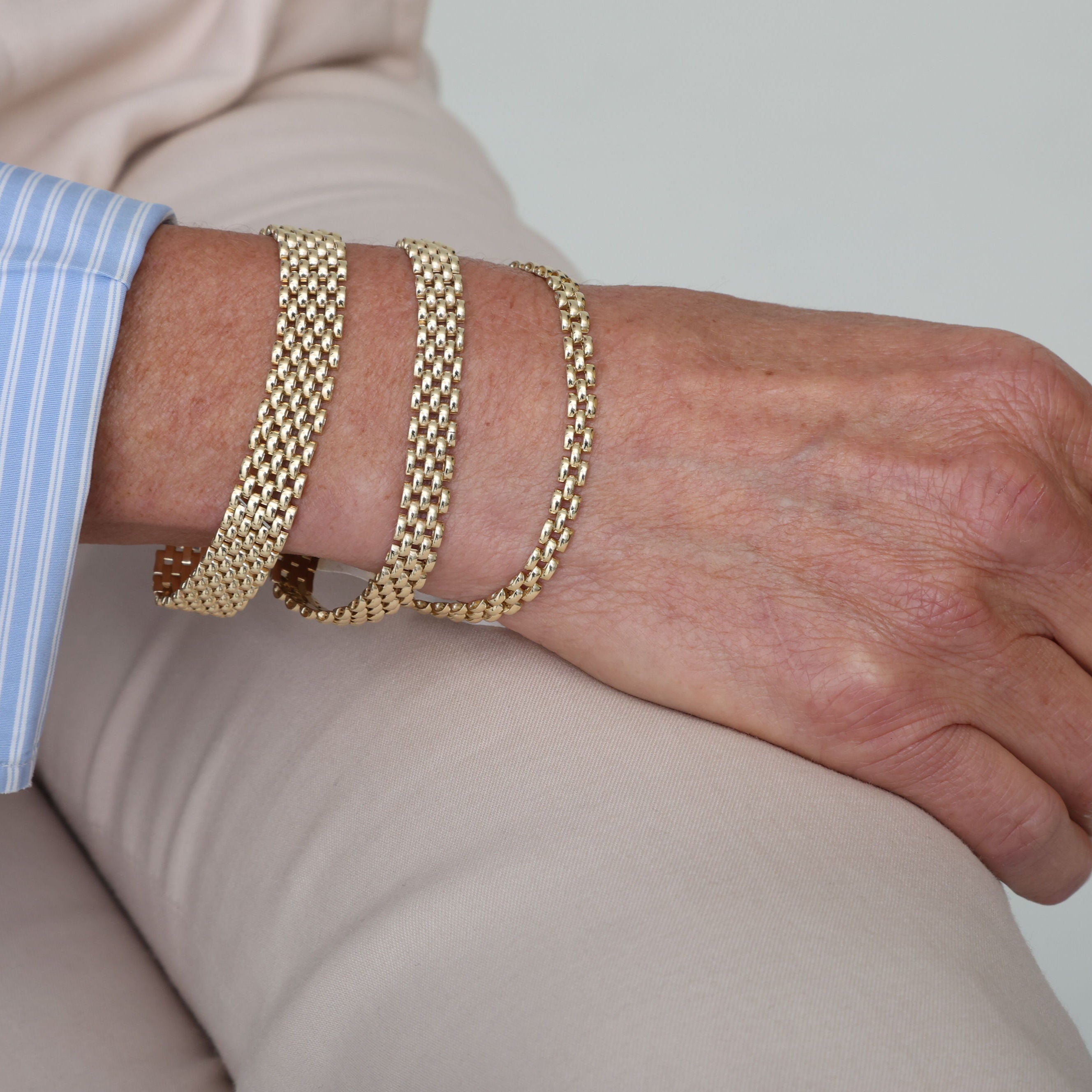 14K yellow gold Panther Link bracelet styled on the wrist with a striped blue dress shirt and beige trousers. The bold link design adds confidence and timeless appeal to professional attire, perfect for workdays, business meetings, and formal events.