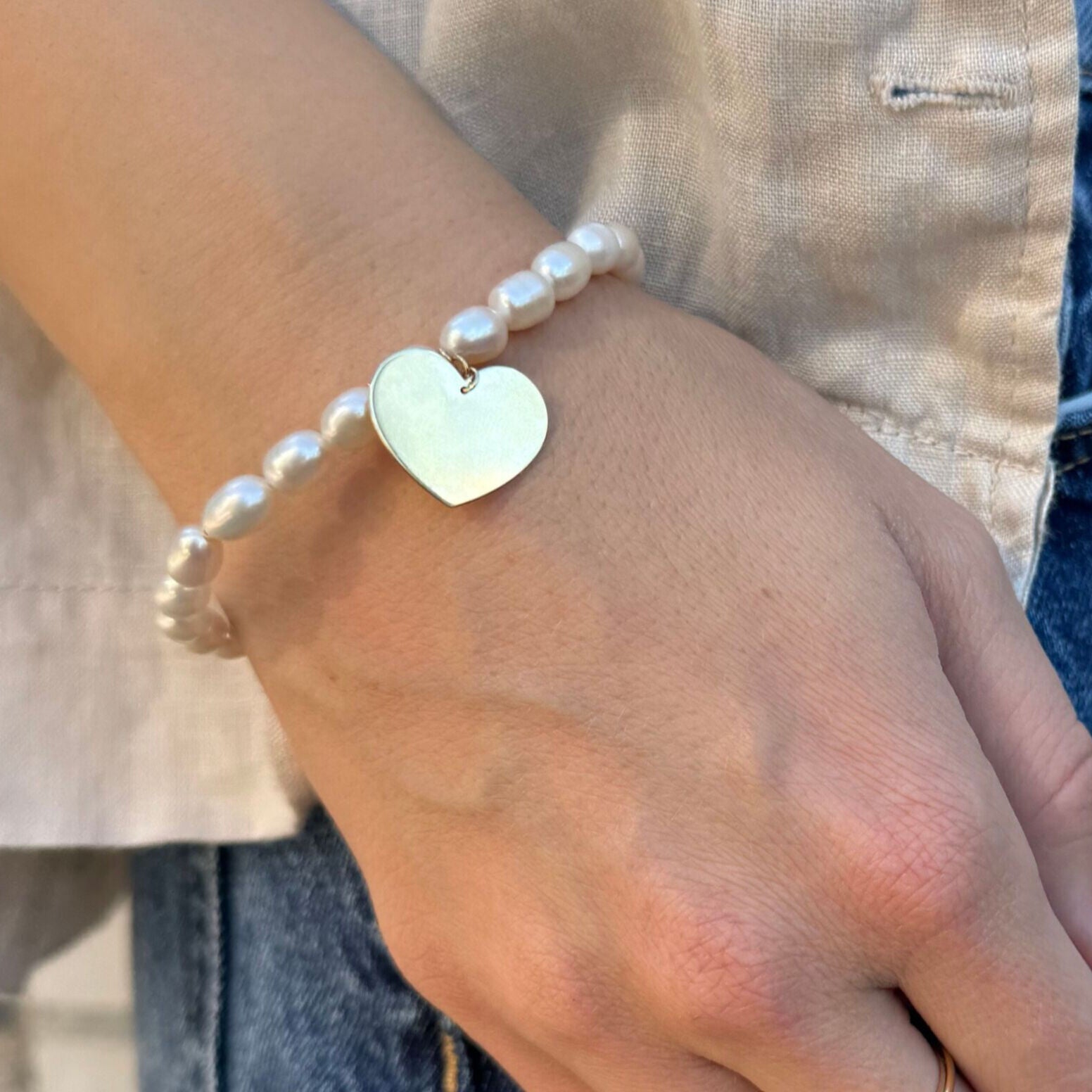 Pearl Bracelet with Heart Charm styled on wrist with casual jeans and a light neutral blouse, adding elegance and timelessness to an everyday look, perfect for brunch dates and casual meetings.
