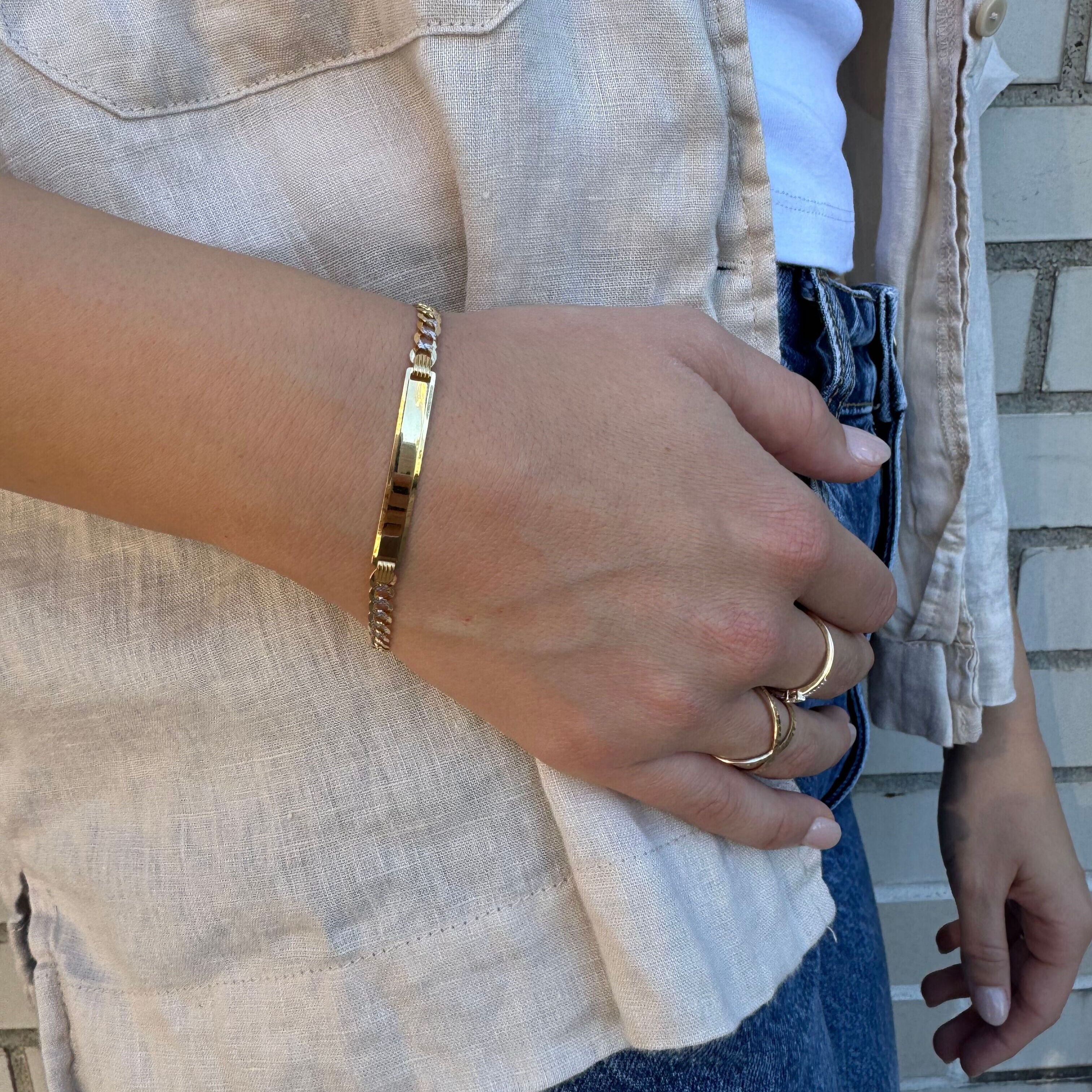 14K Two Tone Gold ID Curb Link Bracelet styled with denim jeans and a beige overshirt, adding a confident touch to a relaxed outfit. A versatile piece perfect for casual meetings, brunch, and everyday wear.